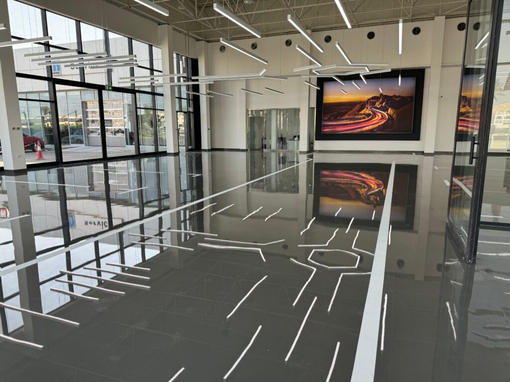 Mirror-gloss epoxy self-level floor reflecting pendant lighting in a Dubai commercial interior
