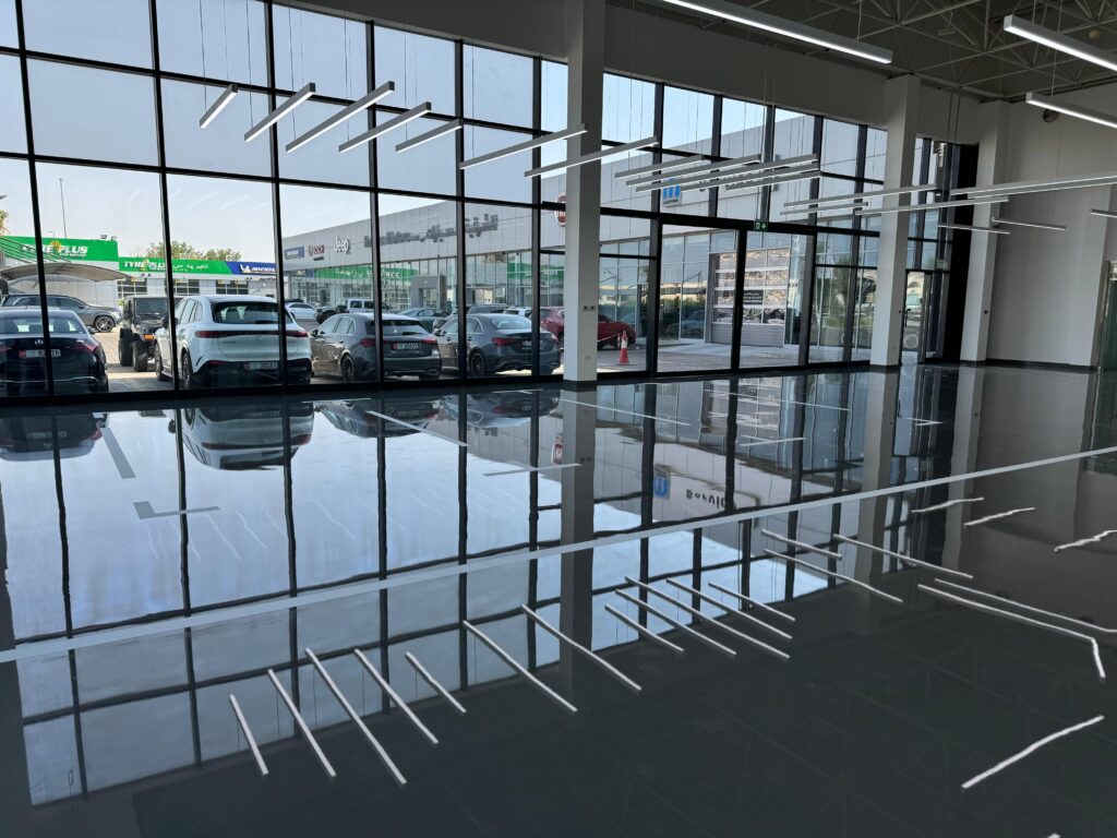 Mirror-finish epoxy self-level flooring reflecting overhead lighting in a Dubai commercial showroom